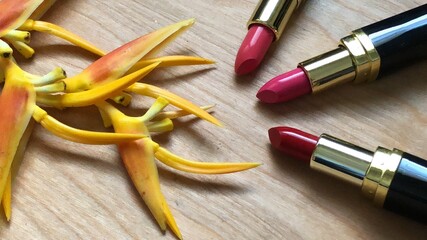 Set of makeup,cosmetics,Red matte lipstick and beautiful Heliconia flowers bouquet on wood...