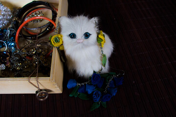 White cat figurine, jewelry box, multi-colored decorations on wooden background