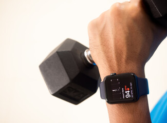 Black watch The screen is displaying heart rate data. In the exercise of a man Who is lifting dumbbells Wearing a blue shirt and white background, concept watches for health