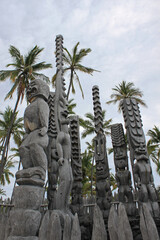 Ki’i or wooden polynesian god sculptures with huge palm trees in the background welcome the...