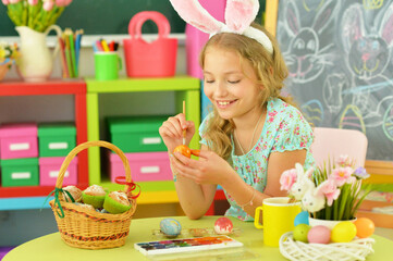 beautiful  girl in bunny ears painting  eggs for Easter holiday