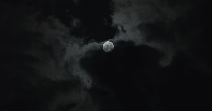 Clouds gathering around full moon at night time