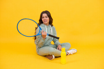 unhappy kid sit with racket water bottle. child with tennis racquet. teen girl going to drink water