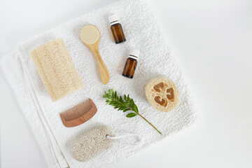 Fototapeta na wymiar flatlet with natural items for personal care. loofah, glass bottles, pumice, loofah, face wash, comb on a white towel. Spa products