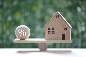 Interest rate up and Banking concept, Model house with Percentage symbol icon on wood scale seesaw...