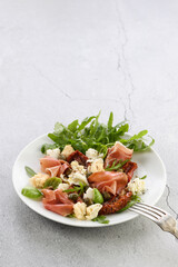 Salad arugula, Parma ham with sun-dried tomatoes, mozzarella slices, croutons, capers, seasoned oil and spices