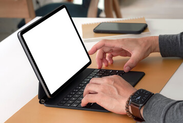 Man hands working on tablet with keyboard while sitting at the table in living room.