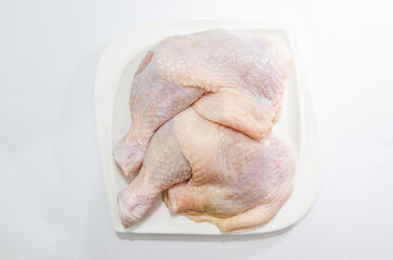 Fresh chicken thighs on a white plate on a white background