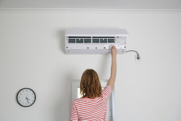 Woman repairing air conditioner at home.