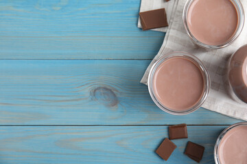 Delicious chocolate milk on light blue wooden table, flat lay. Space for text