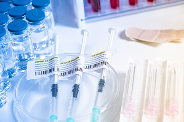 COVID-19 vaccine and syringe. Vials and ampoules with coronavirus vaccine prepared on the doctor or nurse table. Intramuscularly injection vaccination administered by medical professionals.