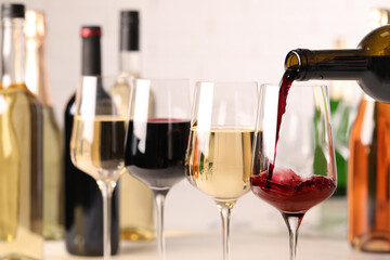 Pouring red wine from bottle into glass, closeup - obrazy, fototapety, plakaty
