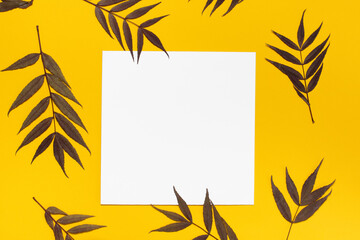 mockup of twigs and a white square sheet of paper on a yellow isolated background. place for your text