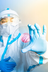 Vaccine researcher with protective clothing in the laboratory with microscope slides and Covid 19 positive blood. Lab technician with a blood sample with a new Coronavirus mutation or variant.