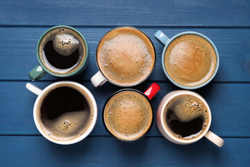 Many different cups of coffee on blue wooden table, flat lay