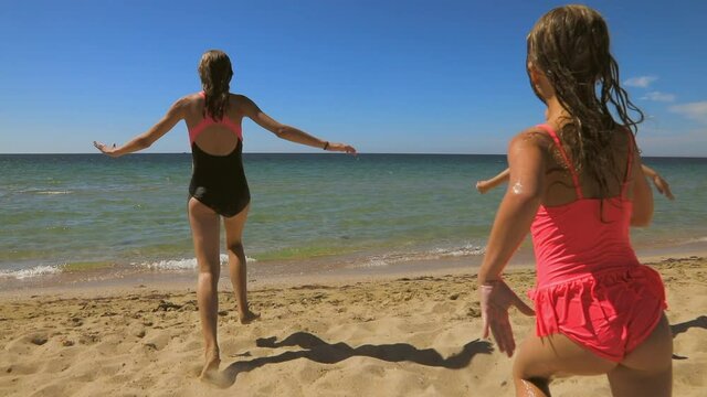 Three children having fun on a beach running to the sea slow motion