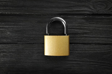 Modern padlock on black wooden table, top view