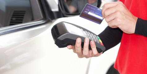 Gas station staff swipe mockup credit card via payment terminal after giving a price quote to the customer sitting in the car.