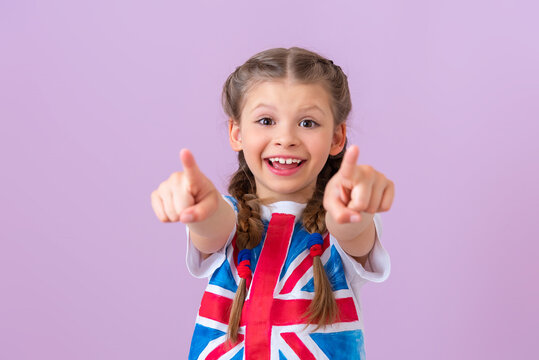 A teenage girl with an English flag points her fingers forward.