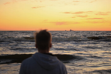 boy on a sea shore at a sunset
