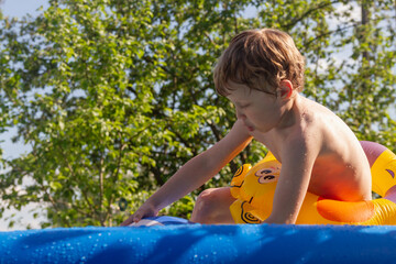 A boy bathes in the heat of summer in a pool with warm water in the garden