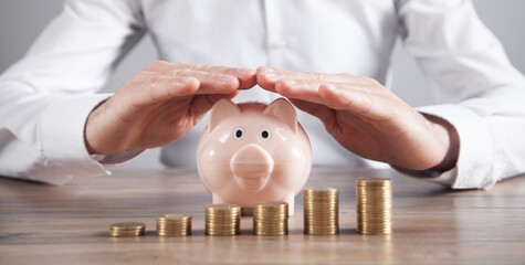 Businessman protect piggy bank and coins. Saving money