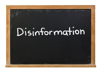 Disinformation written in white chalk on a black chalkboard isolated on white