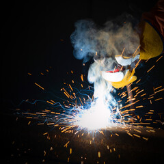 Metal industry workers are welding steel sheet. Sparkler on black background, close-up. Heavy work in factory.