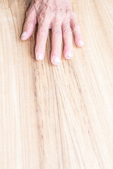 Old man's hands and fingers on wood texture background