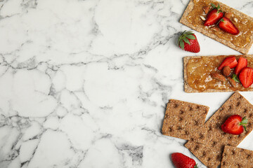 Fototapeta na wymiar Fresh rye crispbreads with jam, strawberries and almonds on white marble table, flat lay. Space for text