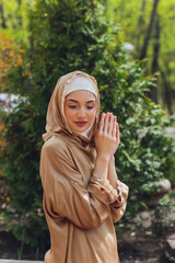 Islamic beautiful woman in a Muslim dress standing on a summer park street background forest autumn...