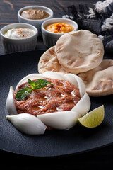 .Raw kebab with side dishes, hummus, babaganoush, curd and pita bread. Arabic food.