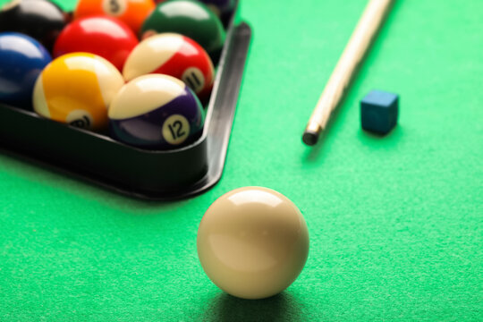 Billiard balls, triangle rack, chalk and cue on green table