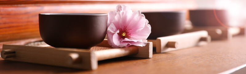 Cup with sakura flower for traditional tea ceremony on wooden table. Banner design