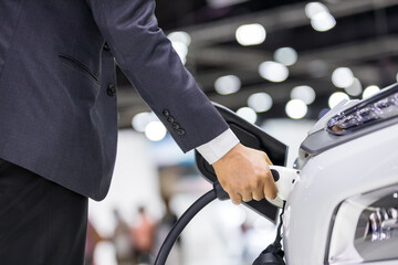 Hand holding Electric car charger. Electric Vehicle EV Charging station and Charger. Human hand is holding Electric Car Charging connect to Electric car.