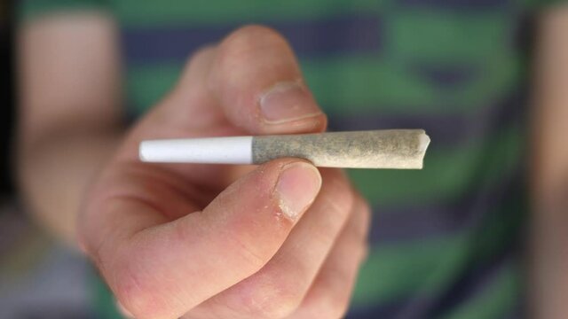 Man showing a marijuana cannabis joint in his hand. Closeup shot.