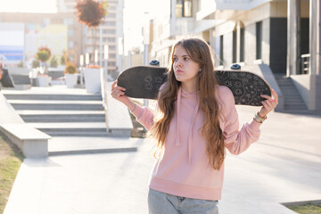 Obraz premium Beautiful ginger teenage girl holding skateboard in her hands. Lifestyle in the city