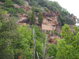hernita de la abellera, santuario de piedra incrustado en la roca, con una entrada principal al edificio con arco adovelado, en el pueblo de prades, tarragona, españa, europa