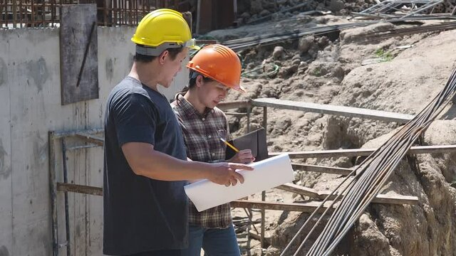 Construction manager and engineer discussing and checking plans on construction site.
