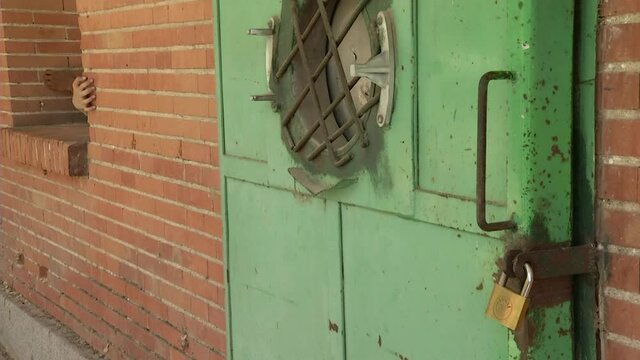 man and woman hands scratching a brick wall with a metal door next to it