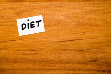 Card with the word "DIET"on wooden table. Close-up view from above