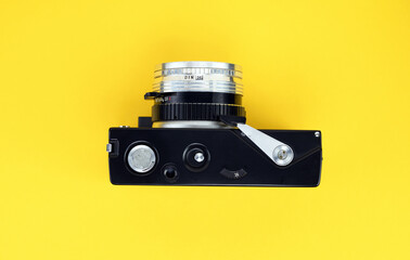 Old retro camera of the 1960s, 1970s in silver color on a yellow background.