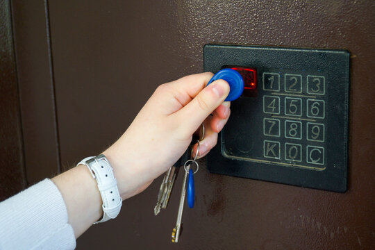  A young woman opens the electronic lock of an iron door with a key fob.