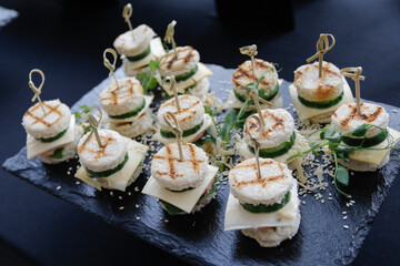 A set of several burgers for catering. Burgers on a black plate on the buffet table. 