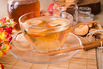 apple tea in cup of glass on the table with fruit in natural. honey and cinnamon