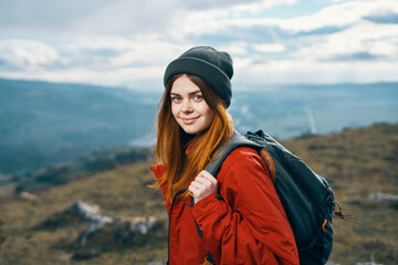 portrait of a traveler In a red jacket and hat and with a backpack outdoors in the mountains fresh...