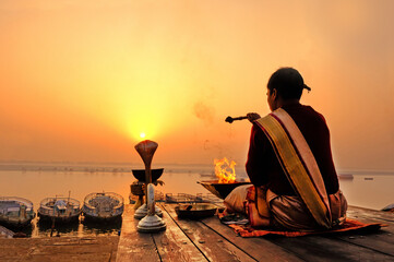 An Unidentified Hindu Brahman monk meditates on the ghat stairs of holy Ganges river - obrazy, fototapety, plakaty