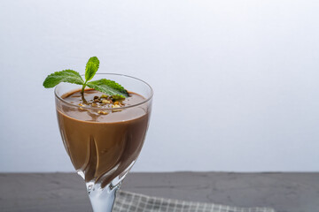 Chocolate cocktail with nuts and mint in a glass on a blue background on a napkin.