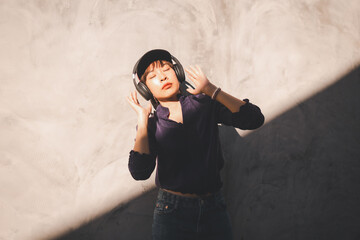 Happy young asian woman listening to music with headphones on the street.