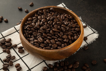 Coffee beans in wooden bowl on grunge background.
